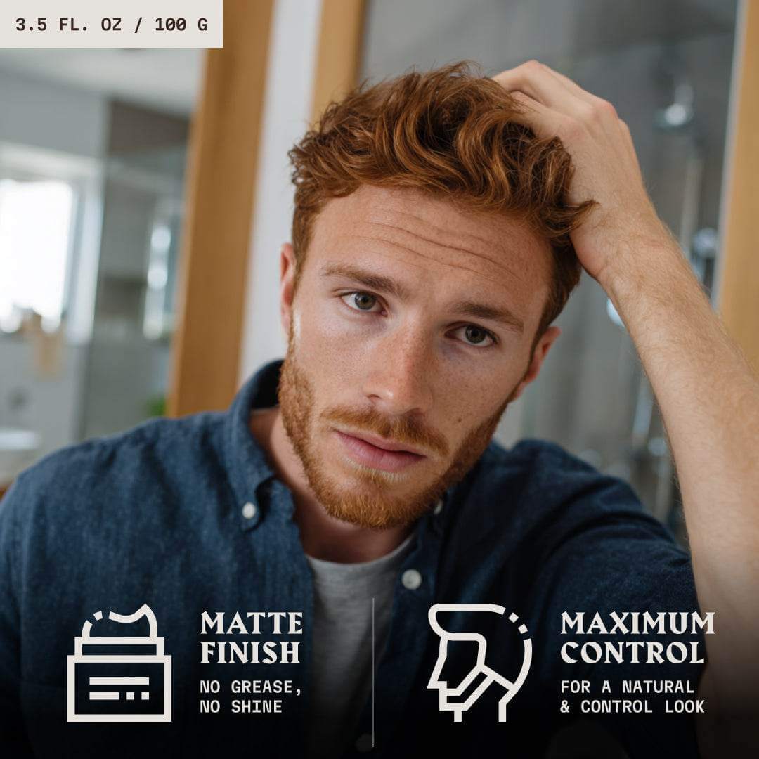Man with red hair adjusting his hair
