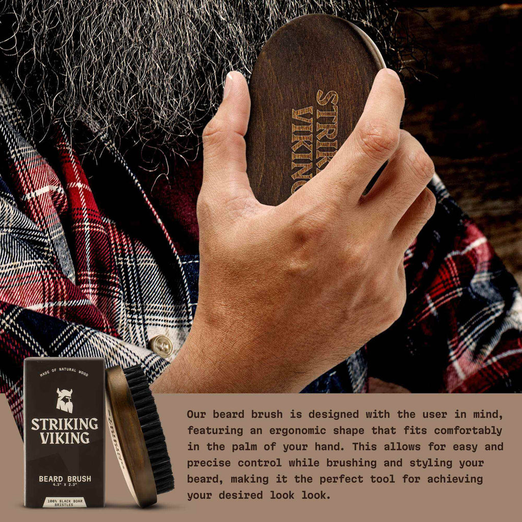 Hand holding a wooden beard brush with 'Striking Viking' branding