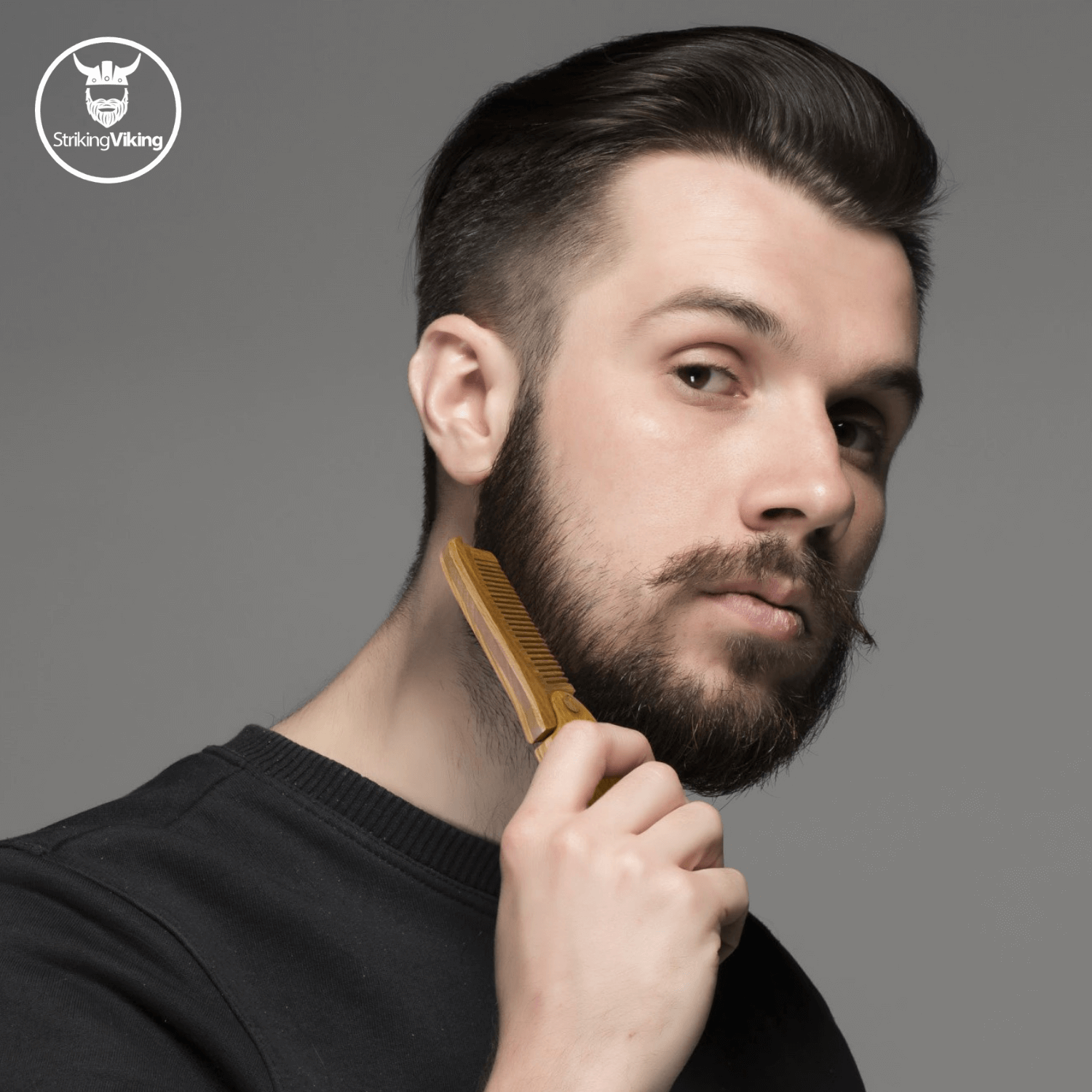 Man with a beard holding a comb against a gray background